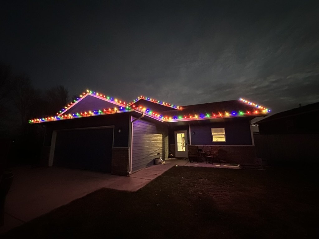 Home roofline outlined in multicolor lights at night